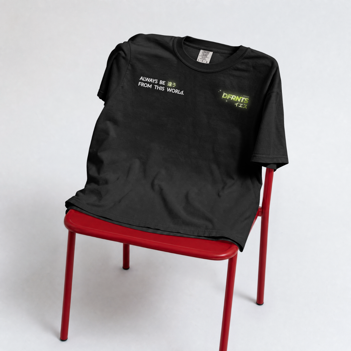 Frente da camiseta preta Always Be Different sobre uma cadeira vermelha